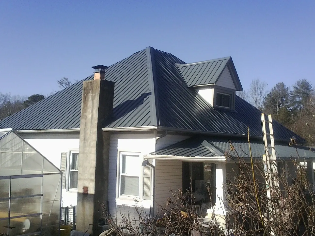 Dark blue standing seam metal roof on a white farmhouse with dormer — Slate & Tile Roof Repair by Roofing Brothers in Shipshewana
