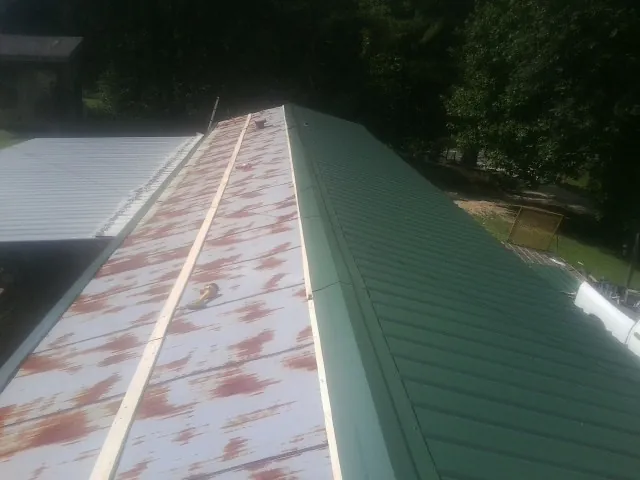 Old rusted panels beside newly installed green metal roofing — Wind Damage Roof Repair by Roofing Brothers in Shipshewana