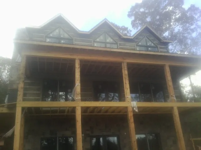 Dormers and porch framing on a large log home under construction — Roof Coating work by our crew in Shipshewana
