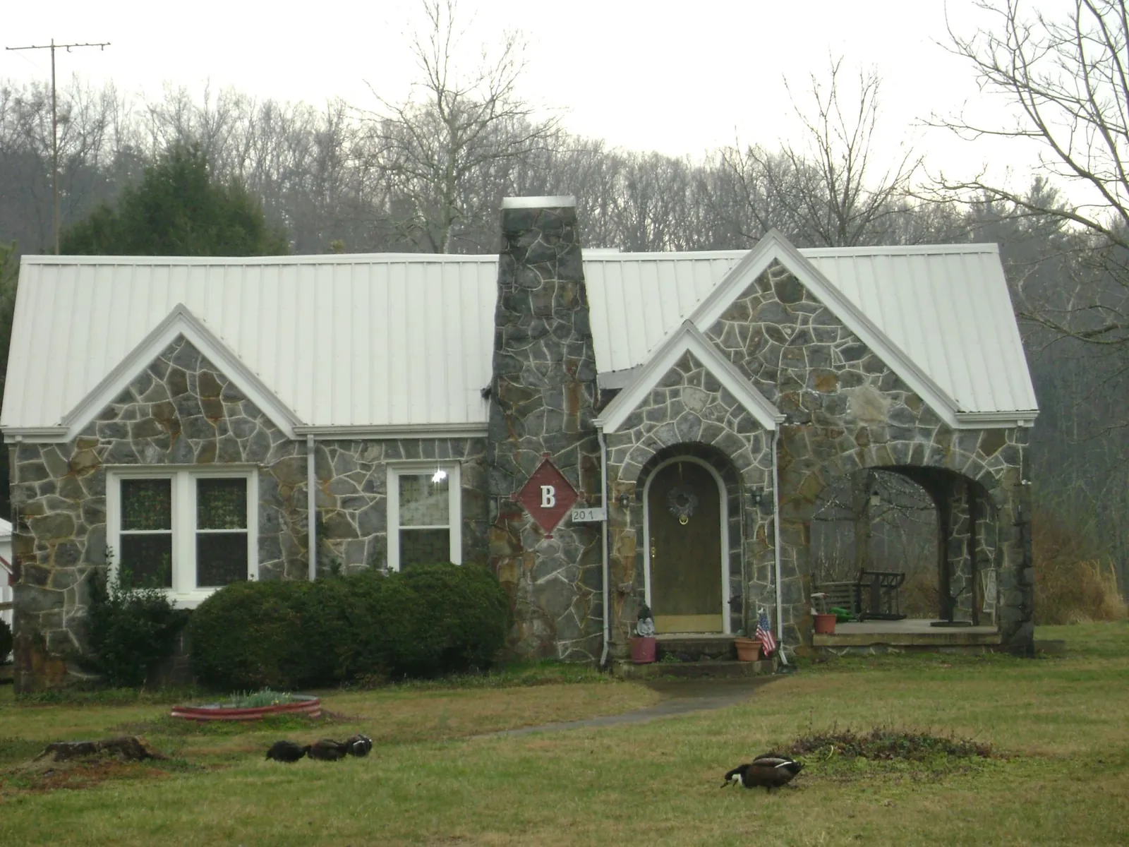 White metal roof on a stone cottage with steep gables in Shipshewana