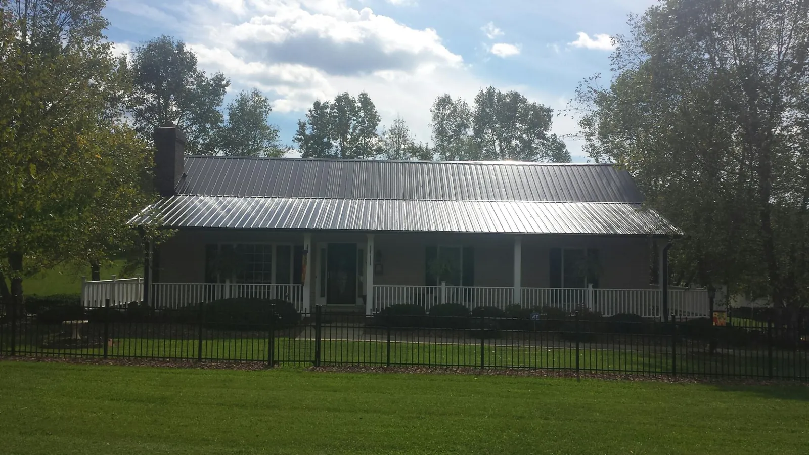 Gray metal roof on a brick ranch with a full width front porch — Gutter Guard Installation work by our crew in Shipshewana