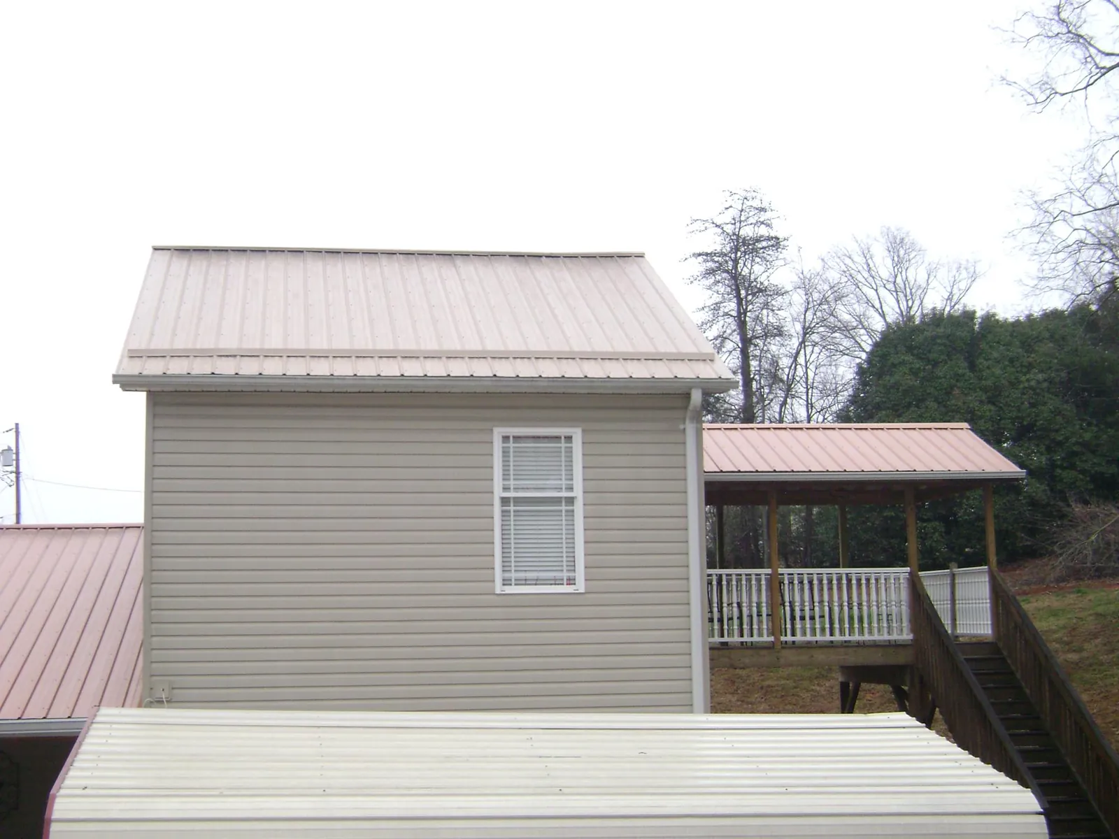 Tan metal roofs on a two story addition and attached porch, from a Roof Replacement job in Shipshewana