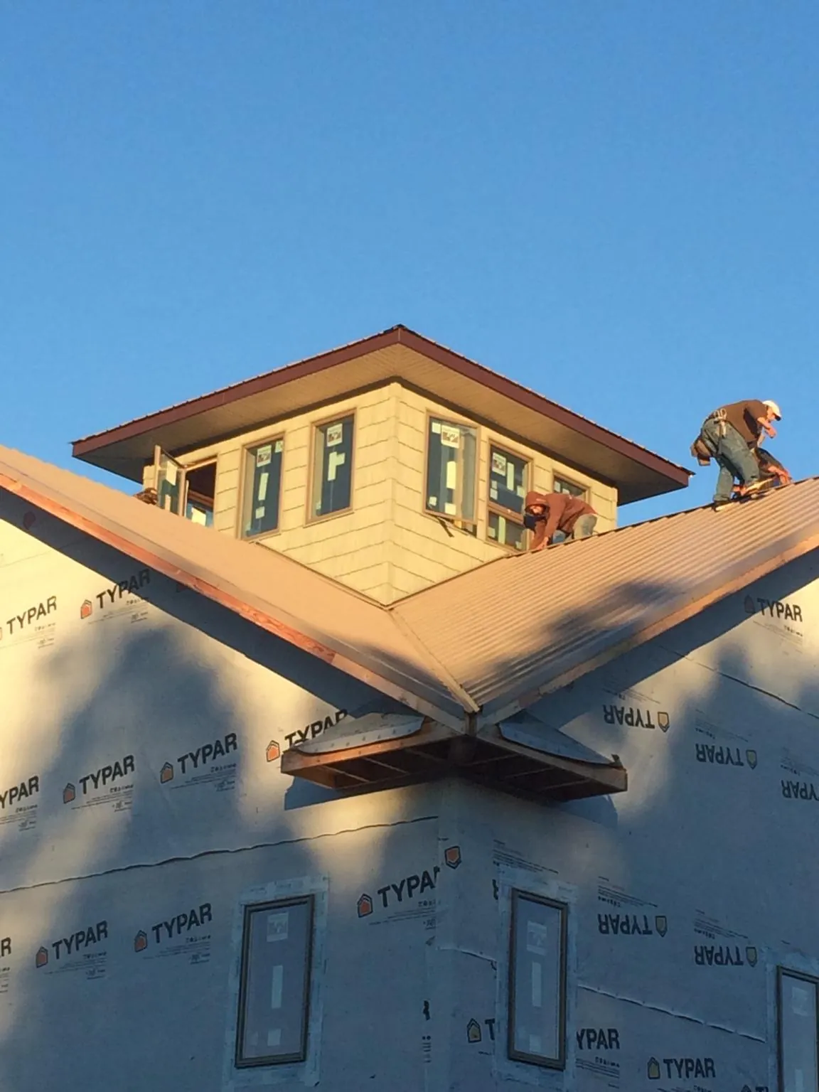Roofers working around a rooftop cupola on a new metal roof at sunset — Roof Waterproofing in Shipshewana by Roofing Brothers